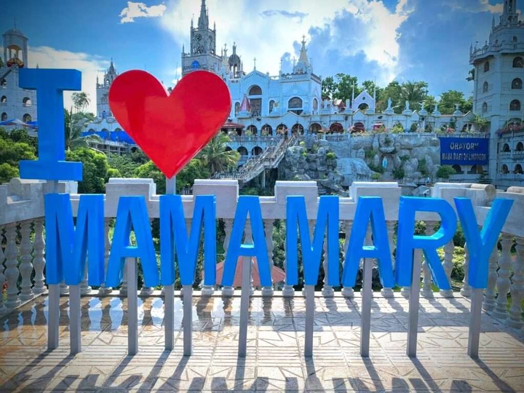 Simala Shrine 2024: A Journey to the Miraculous and Mystical Castle Church in Cebu 2 It is a sign saying "I love Mama Mary". The background is the castle like shrine called Simala.